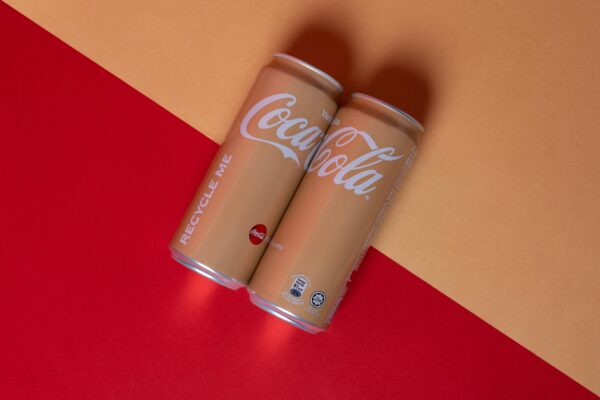 Studio shot of Vanilla Coca-Cola cans on vibrant red and yellow background.